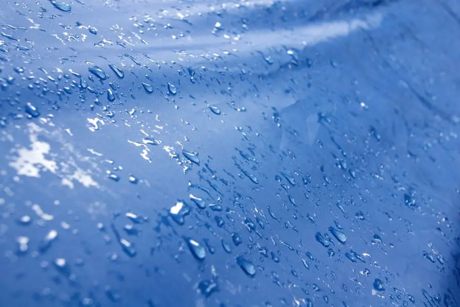 Photo of a blue rain tarp with water droplets shimmering in the sun.