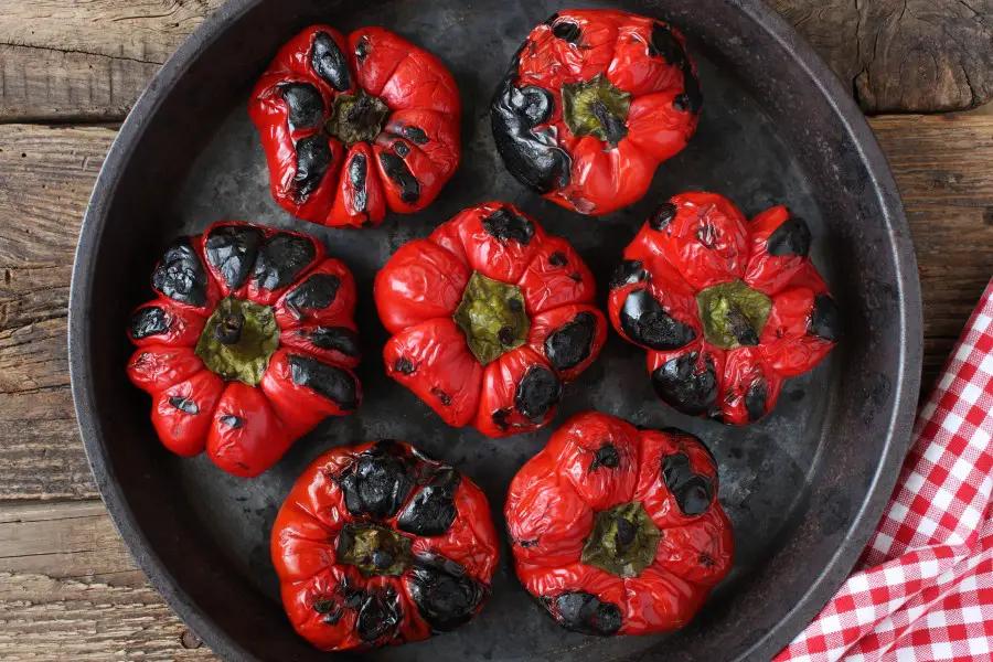 Photo of 7 roasted red bell peppers with charred toped