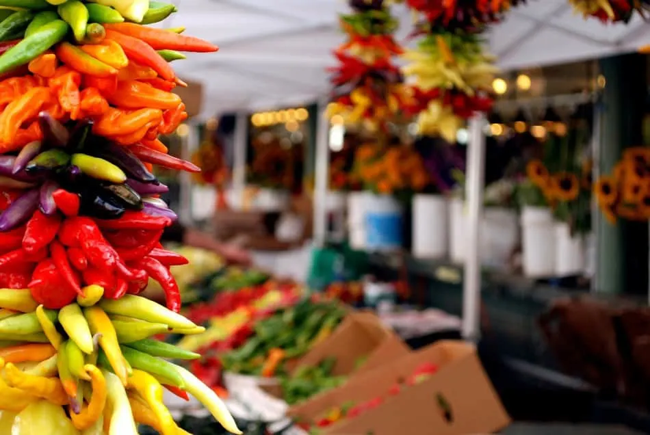Photo of a farmers market with strung chili peppers hanging in the foreground