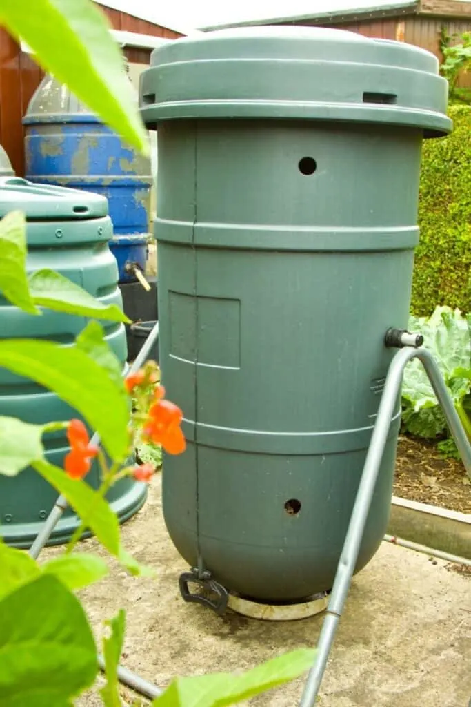 Photo of tall green circular rotating composter. The composter looks to be about hip high tall and is supported by two triangular metal supports on either side.