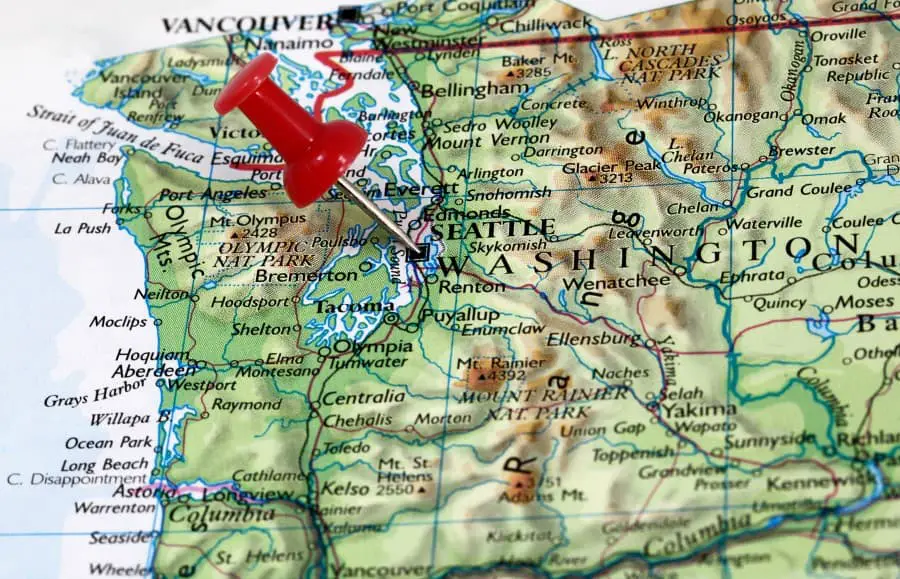 Photo of the Washington state map with a red thumb tack pinned to Seattle at angle