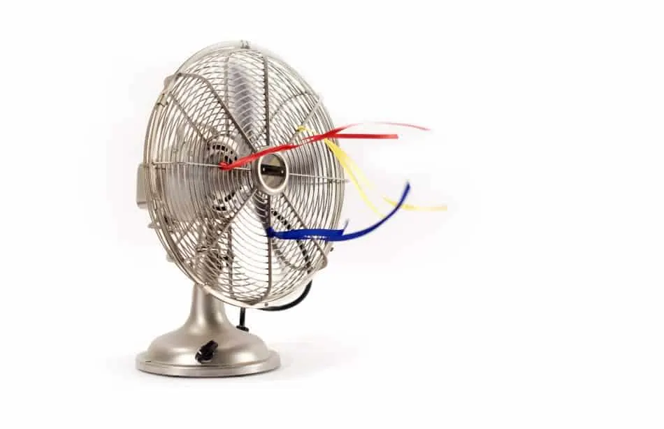 Photo of a vintage fan with streamers tied to the front. The fan is on and the streamers are flowing.