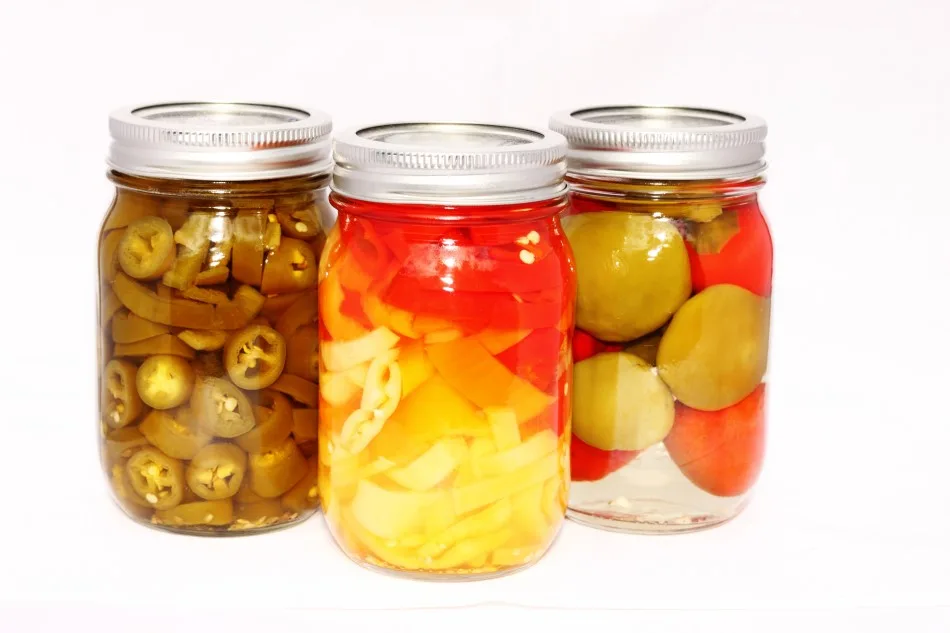 Photo of 3 jars of fermented canned peppers set against a white backdrop