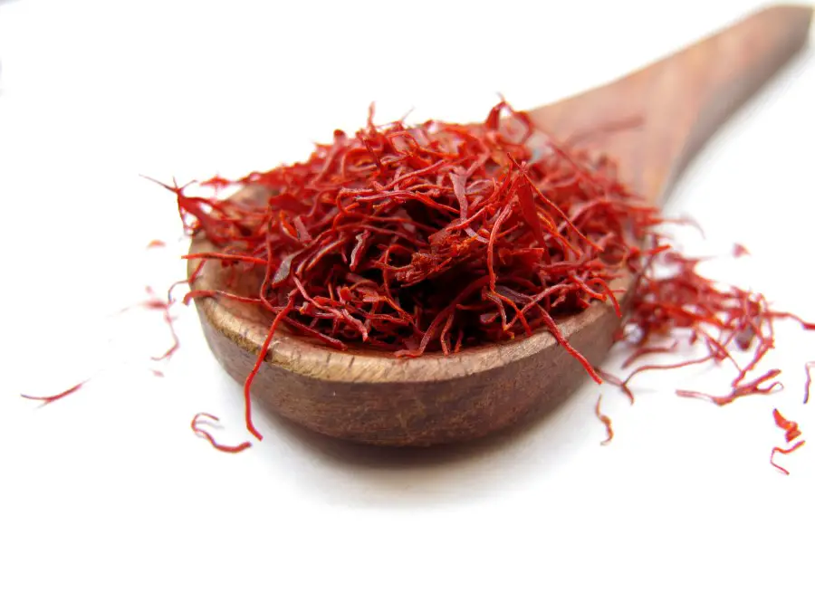 A wooden spoonful of saffron on a white backdrop