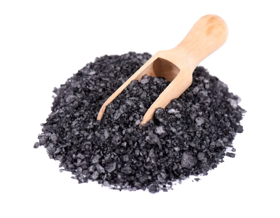 Photo of black salt pilled up with a small wooden spoon sitting on top of the pile