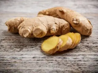 Photo of whole and sliced ginger set on a wooden table