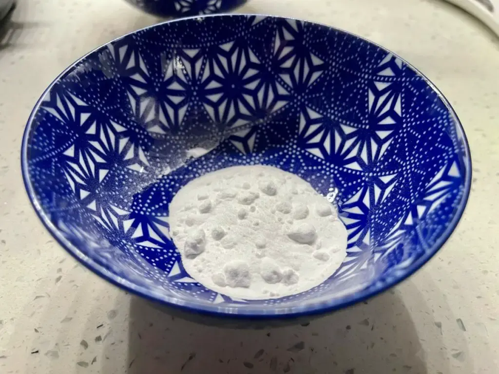 Baking soda sitting at the bottom of a small patterned blue bowl.