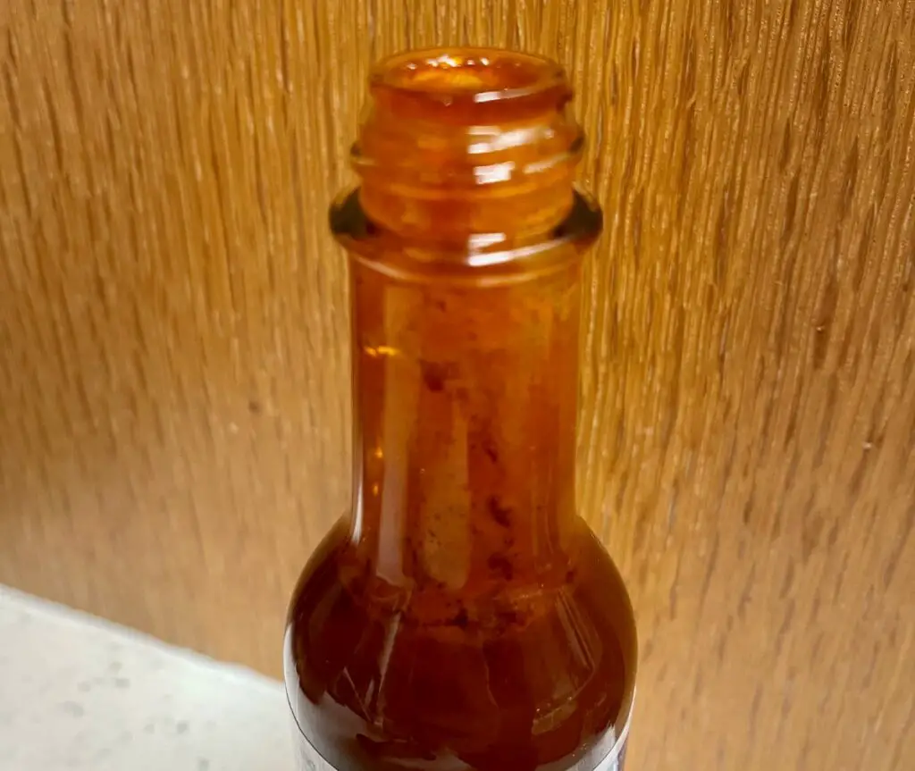 Photo of an open bottle of hot sauce that has turned brown
