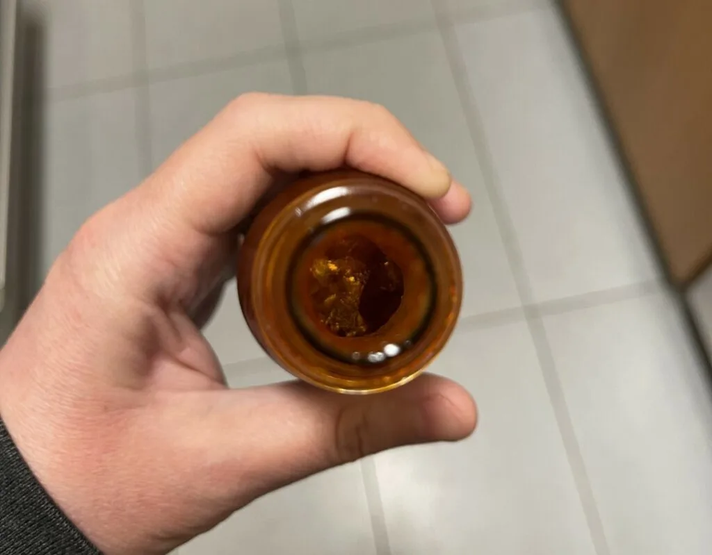 Looking down inside an open bottle of hot sauce to see if it has gone bad