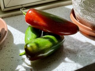 A stack of very large Jalapeño peppers ranging from green to red in color